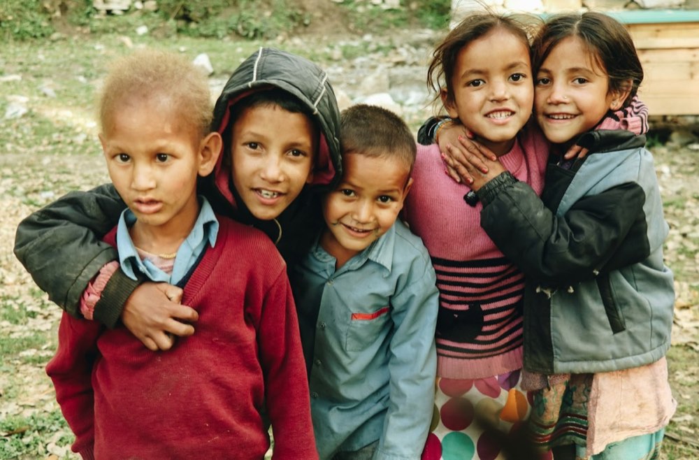 Four smiling children hugging each other outdoors