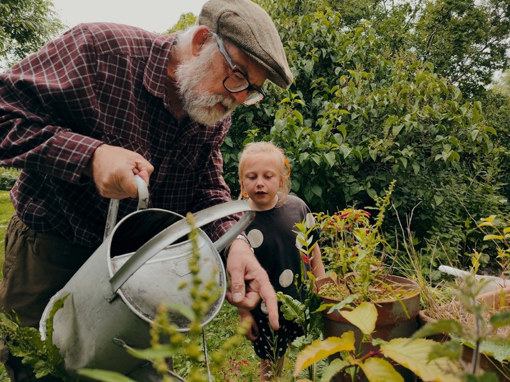A grown-up and a child watering plants in a garden